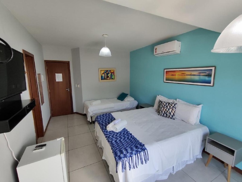 Quarto da Estalagem dos Corais da Prainha com cama de casal e de solteiro, TV e parede azul