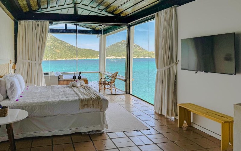 Quarto do Recanto do Atalaia com cama de casal, TV e vista para as Prainhas do Pontal do Atalaia