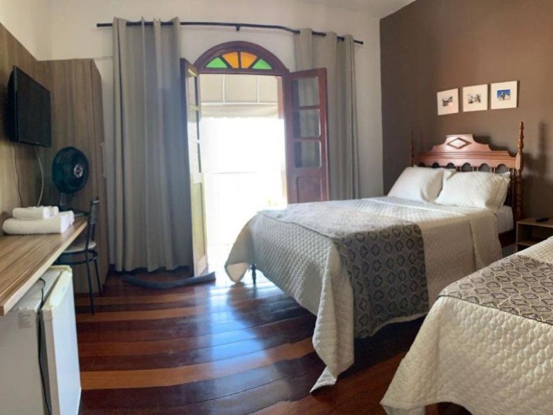 Quarto da Pousada da Seresta, dica de onde ficar em Diamantina, com duas camas, TV e piso de madeira