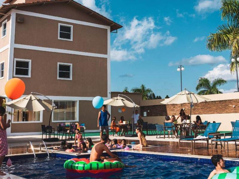 Pessoas se divertem na piscina do Estilo de Minas, dica de pousada em Diamantina, em dia de céu com poucas nuvens