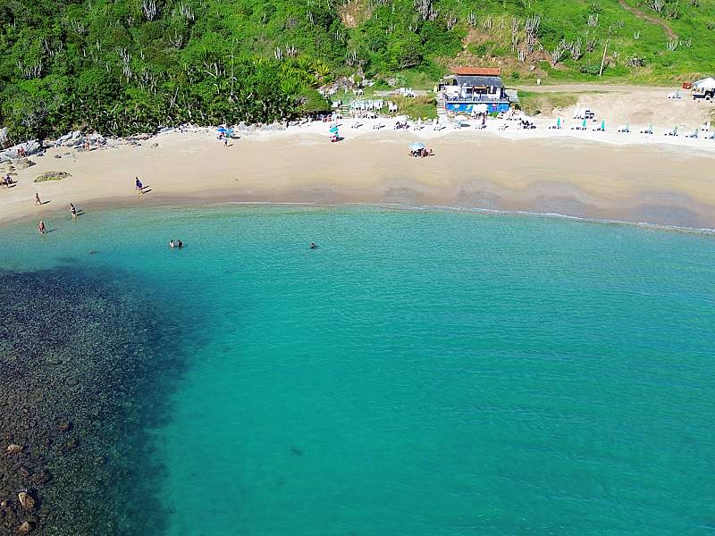Vista de algumas barracas na orla e mar cristalino