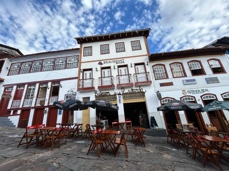 Bares da Rua da Quitanda, dica de o que fazer em Diamantina, com mesas vazias e céu azul com nuvens