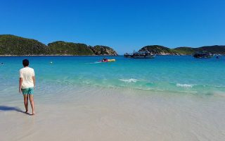 Homem visto de costas na areia da Ilha do Farol em Arraial do Cabo