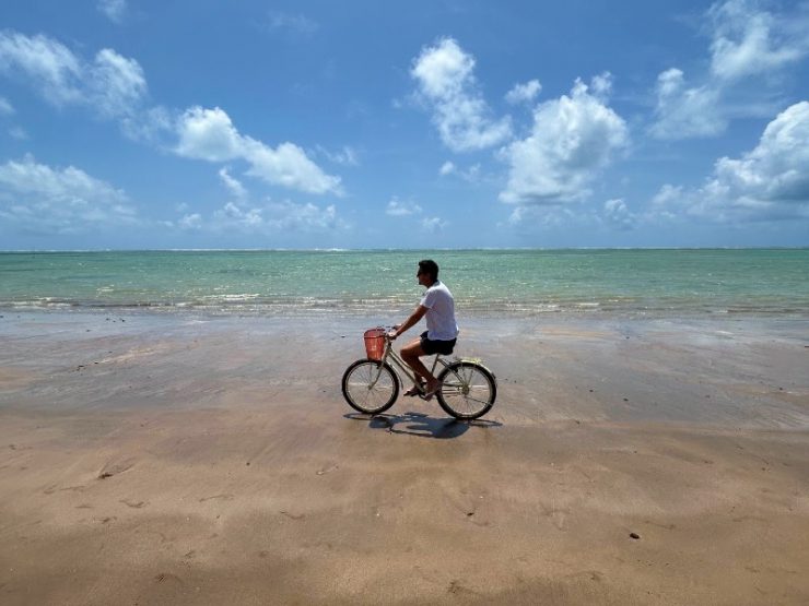 Homem anda de bicicleta na maré baixa da Praia do Patacho, dica de o que fazer em Porto de Pedras