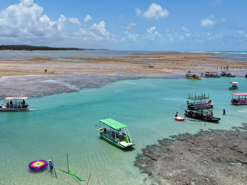 Jangadas paradas nas águas claras da Piscinas Naturais do Patacho, dica de o que fazer em Porto de Pedras