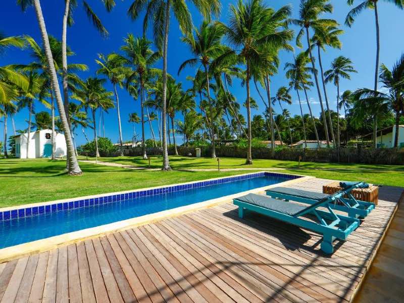Piscina da Pousada Patacho com igrejinha à frente em dia de céu azul