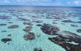Homem boia na água cristalina dos Parrachos do Rio do Fogo, no Rio Grande do Norte