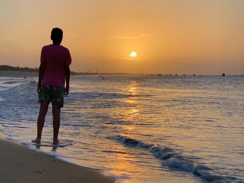 Homem observa o sol se pondo no mar em São Miguel do Gostoso, RN