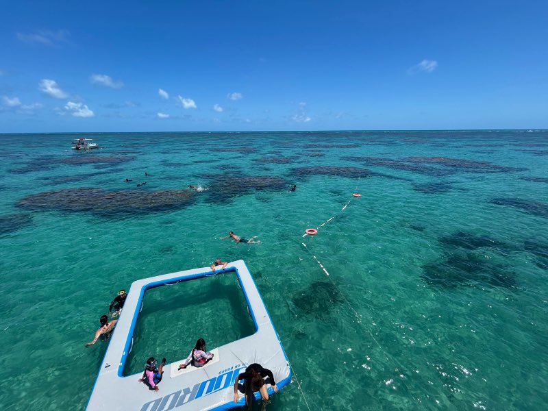 Pessoas nadam nos Parrachos de Maracajaú em dia de céu azul