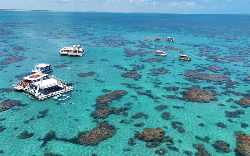 Barcos parados e vistos de cima nas águas cristlainas dos Parrachos de Maracajaú