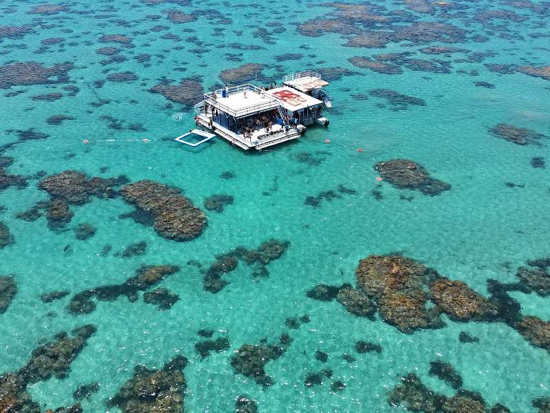 Vista de cima dos Parrachos de Maracajaú com catamarã de apoio em águas verdes cristalinas