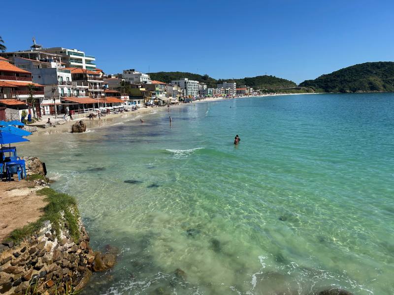 Pessoas nadam no mar esverdeado e cristalino da Prainha, em Arraial do Cabo