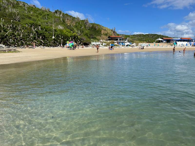 Mar calmo e esverdeado da Praia das Conchas, dica de o que fazer em Cabo Frio, em dia de céu azul
