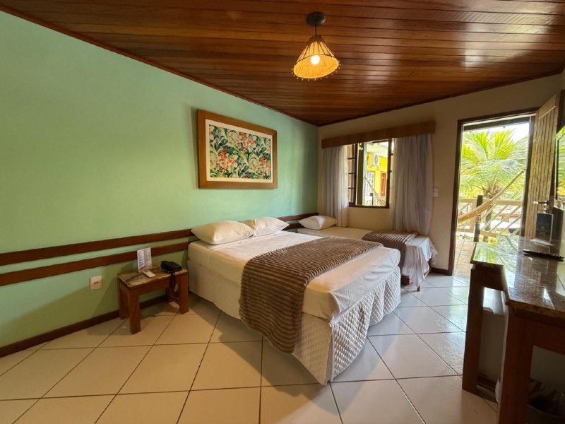 Quarto do Hotel Mar de Cabo Frio com cama de casal e de solteiro e parede verde