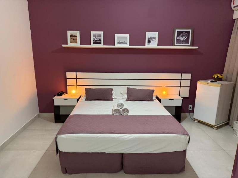 Quarto do Hotel Marlen com cama de casal e parede lilás