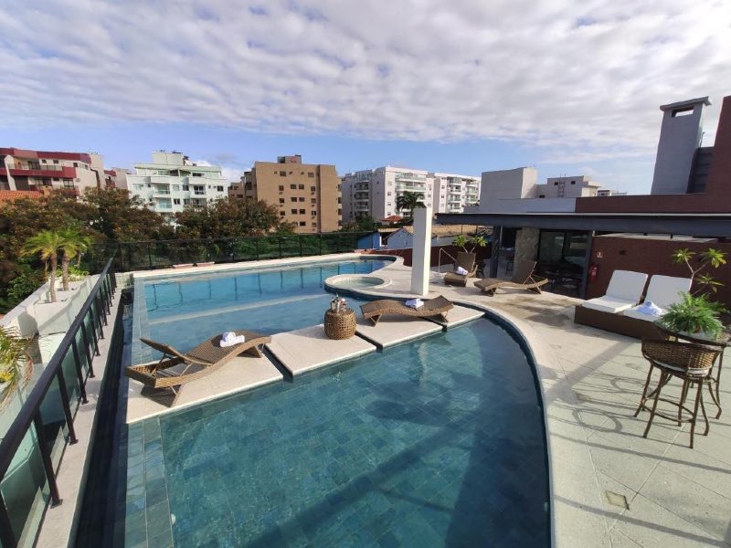 Área externa do Nova Onda, dica de onde ficar em Cabo Frio, com piscina em dia de céu azul com nuvens