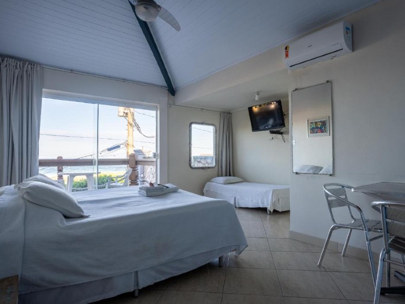 Quarto da Pousada On Shore com cama de casal e de solteiro, mesa e varanda