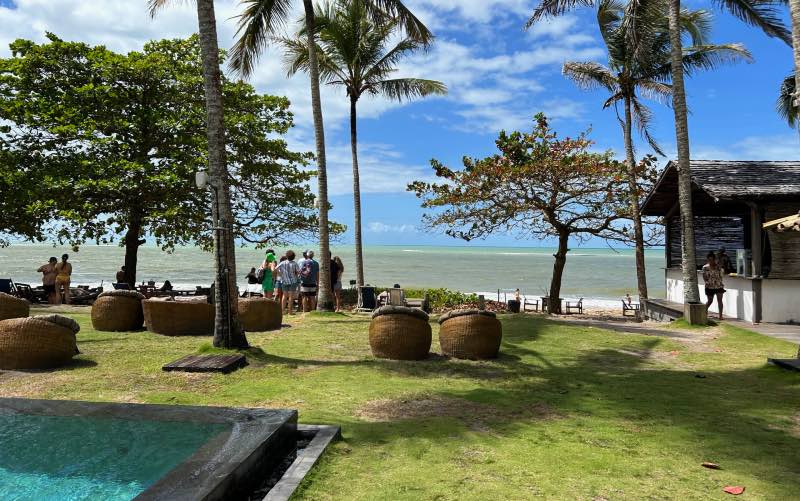 Beach club em Caraíva, uma das praias do sul da Bahia, com mar esverdeado e céu azul com nuvens