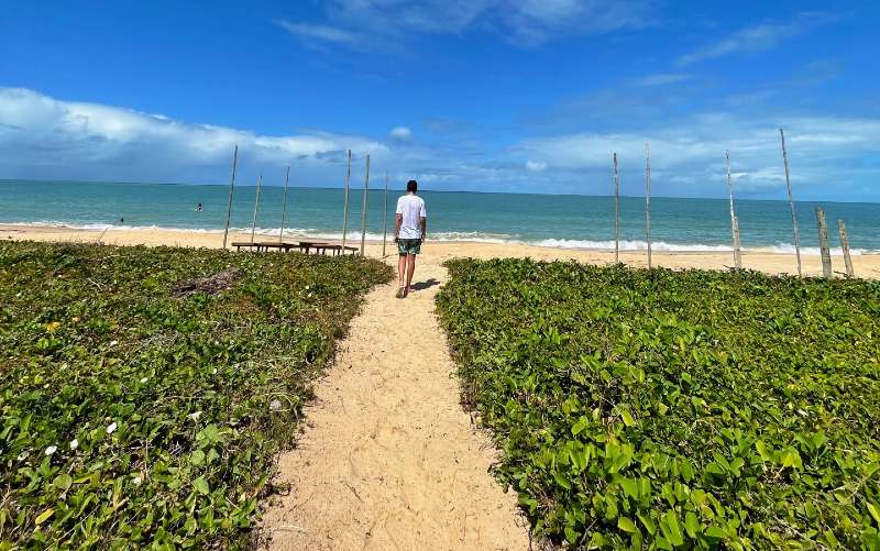 Homem anda em direção à Ponta do Corumbau em dia de céu azul