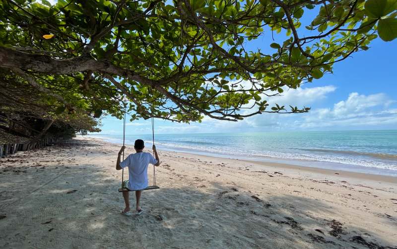 Homem se diverte em balanço de árvore na Ponta do Corumbau