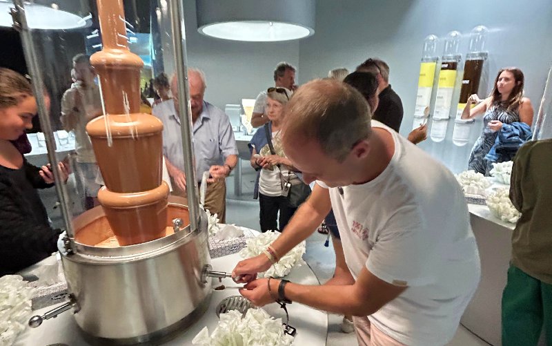 Homem pega chocolate ao leite da fonte no Museu da Lindt, em Zurique