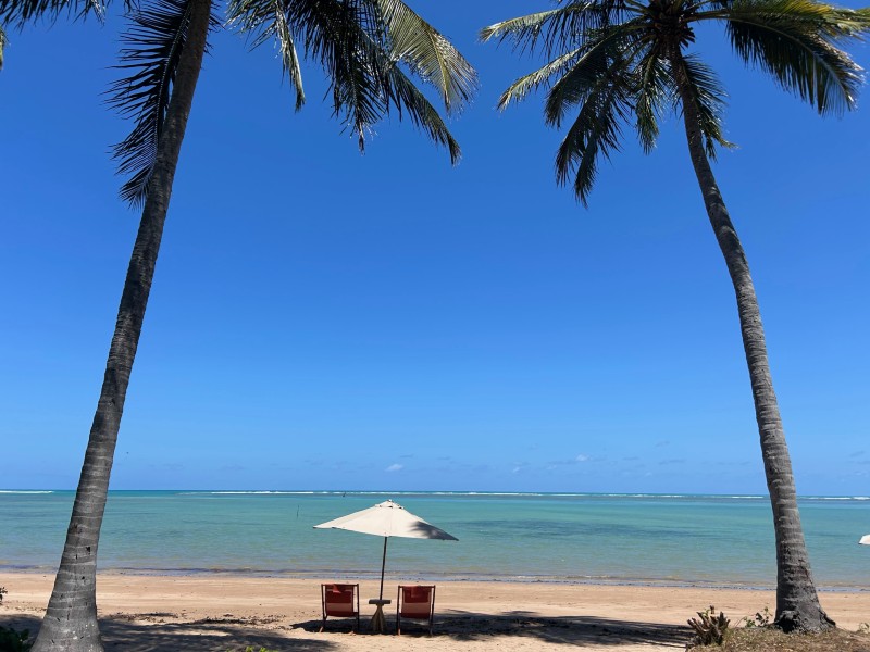 Guarda-sol com duas cadeiras na Praia do Patacho, na Rota Ecológica dos Milagres, em dia de céu azul