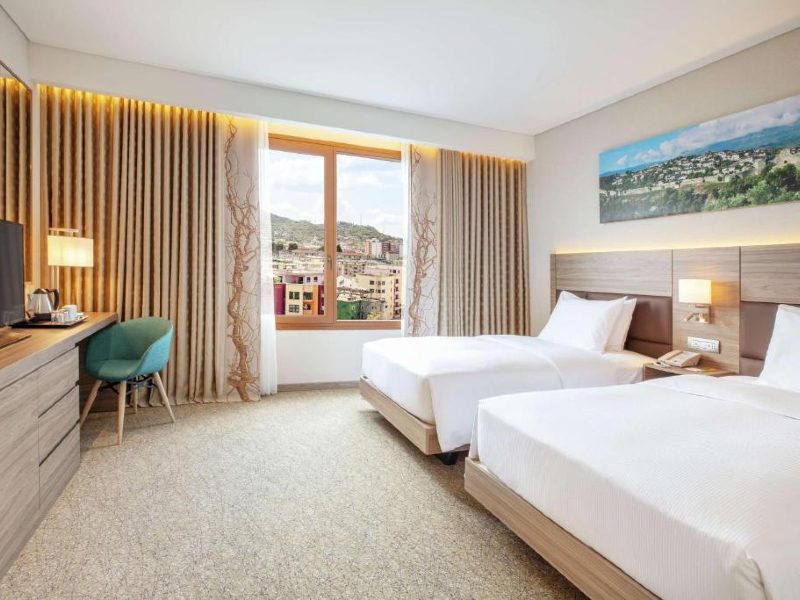 Quarto do Hilton Garden Inn com duas camas, carpete e cadeira azul