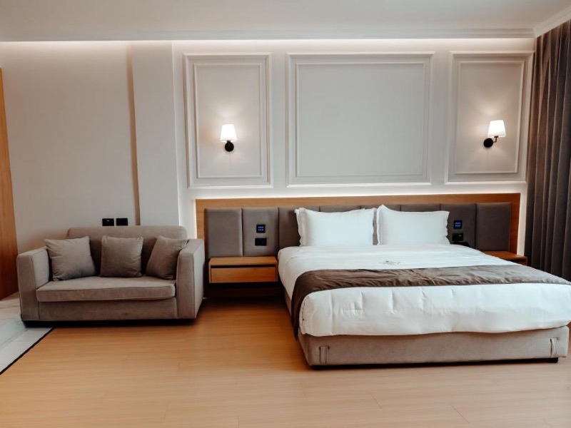 Quarto do Holiday, dica de onde ficar em Tirana, com cama de casal, sofá e piso de madeira