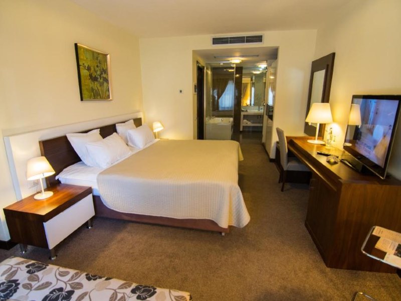 Quarto antigo do Kotoni com cama de casal, carpete e decoração de madeira