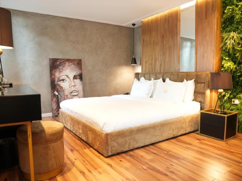 Quarto do La Suíte com cama de casal, piso de madeira e quadro encostado na parede