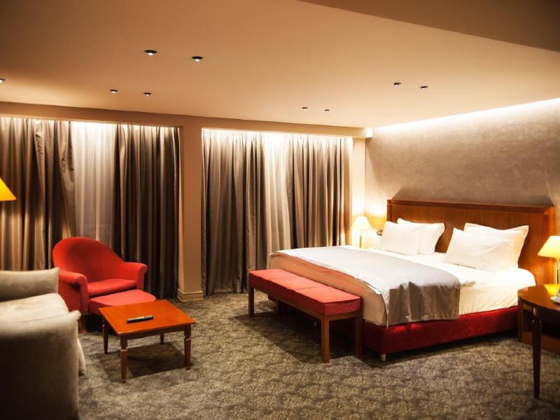 Quarto do Mondial Hotel, dica de onde ficar em Tirana, com cama de casal, carpete e sofá