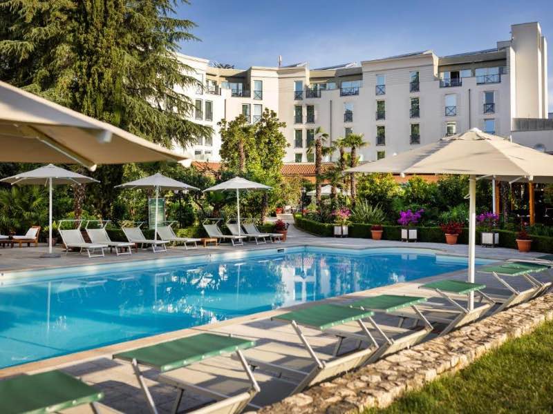 Piscina do Rogner Hotel, dica de onde ficar em Tirana, com espreguiçadeiras vazias em dia de céu azul