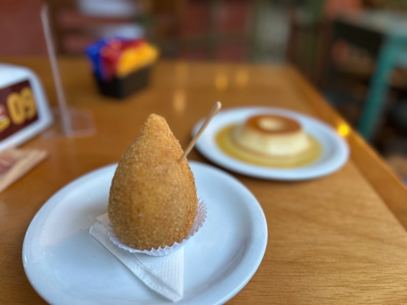 Coxinha com catupiry e pudim ao fundo do Tachão de Ubatuba