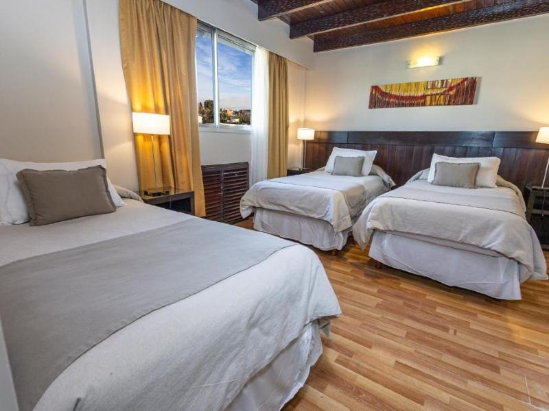 Quarto do Carlos V Patagonia com três camas de solteiro e piso de madeira