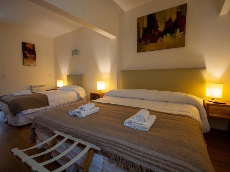 Quarto do NBH Nativo, dica de onde ficar em Bariloche, com cama de casal e de solteiro com abajur ao lado