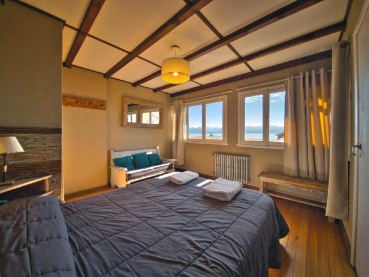 Quarto do Bariloche Hostel com cama de casal, sofá e espelho