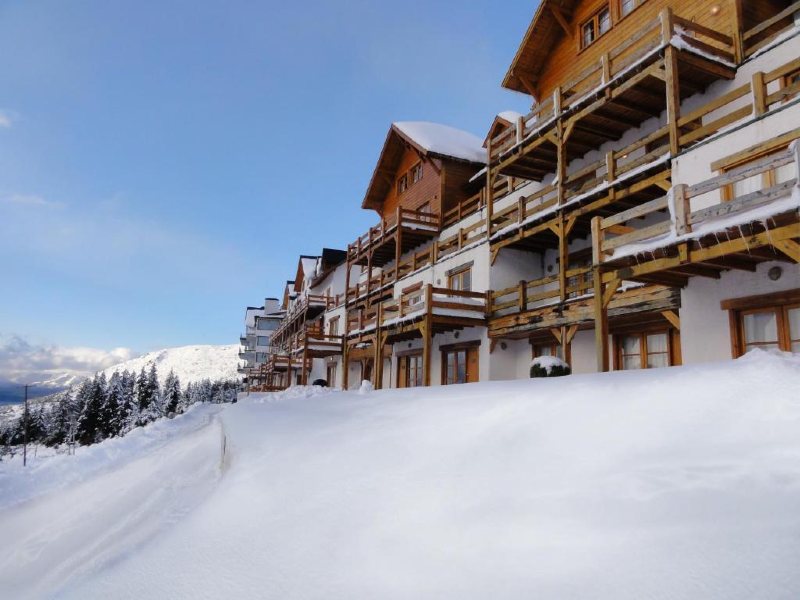 Área externa da Hostería del Cerro com muita neve e céu azul