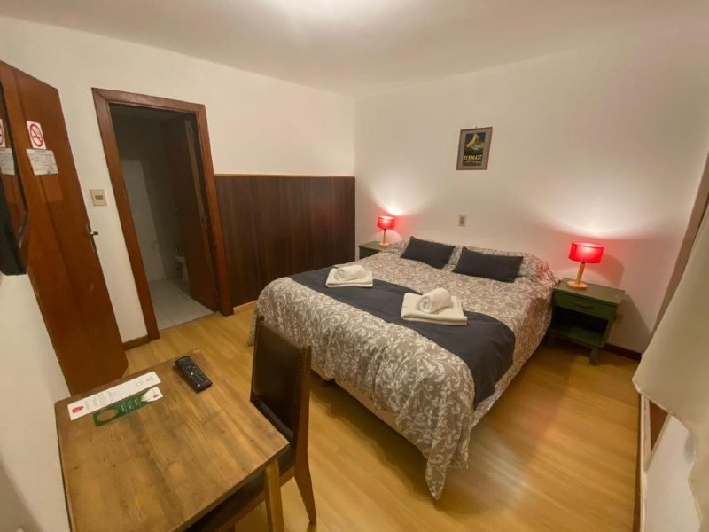 Quarto da Hostería Suiza com cama de casal, piso de madeira e abajur