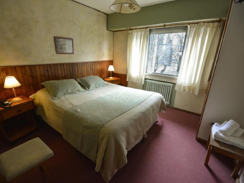 Quarto simples da Hostería Sur, dica de onde ficar em Bariloche, com cama de casal, aquecedor e carpete roxo