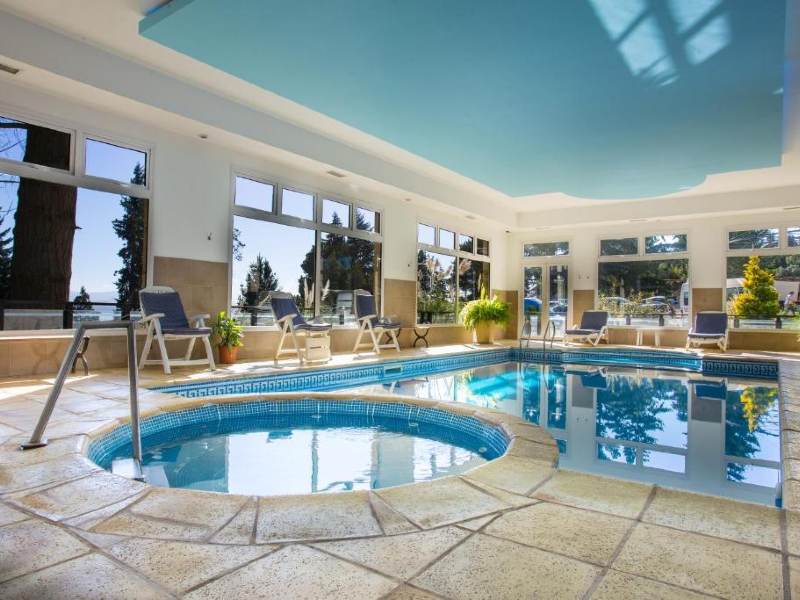 Piscina vazia do Hunid Hotel Pioneros, dica de onde ficar em Bariloche, com janelas grandes e plantas