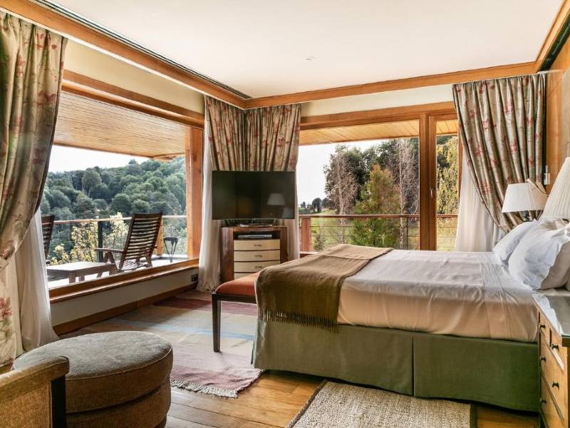 Quarto do hotel Llao Llao com cama de casal, TV, varanda e piso de madeira