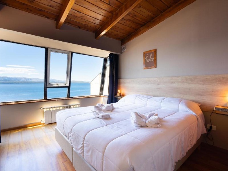 Quarto do Tangoinn Hostel, dica de onde ficar em Bariloche, com cama de casal e vista para o lago