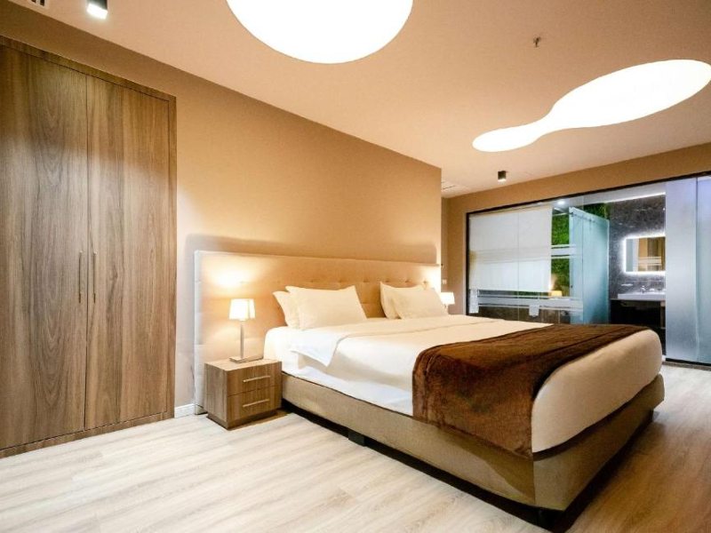 Quarto do Best Western Premier Ark Hotel com cama de casal, piso de madeira e banheiro ao fundo