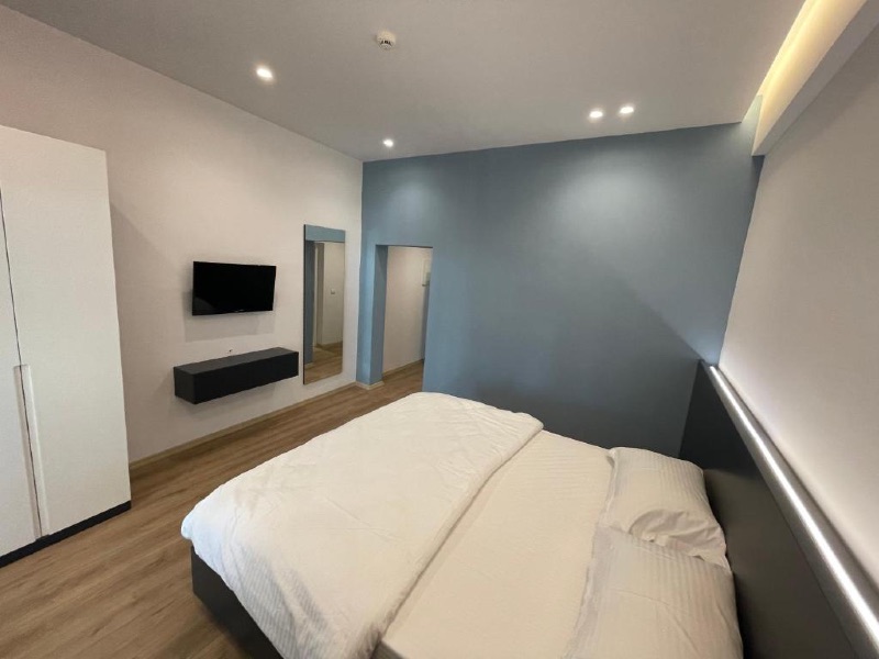 Quarto do Ladi Rooms com cama de casal, TV e parede cinza