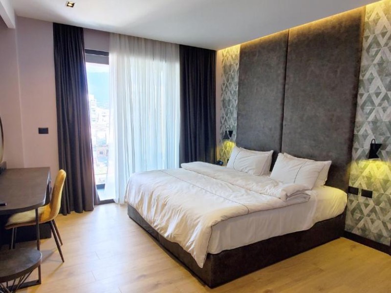 Quarto do Starlight com cama de casal, paredes cinzas e piso de madeira