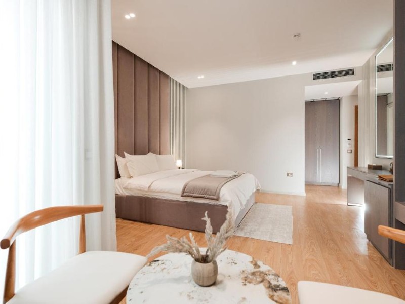 Quarto espaçoso do Troci, dica de hotel em Tirana, com cama de casal, mesa e piso de madeira