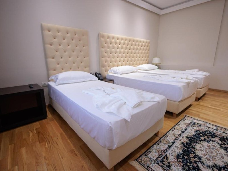 Quarto do Ufo Hotel, dica de onde ficar em Tirana, com três camas de solteiro e cabeceira clara