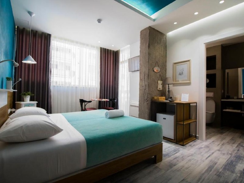 Quarto do Urban Rooms com cama de casal com roupa de cama verde