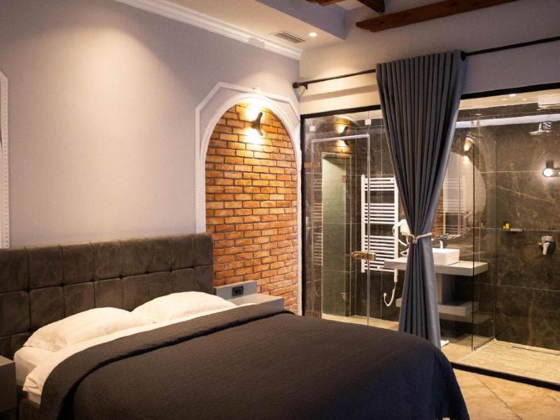 Quarto do Venis com cama de casal e vista do banheiro com vidro transparente