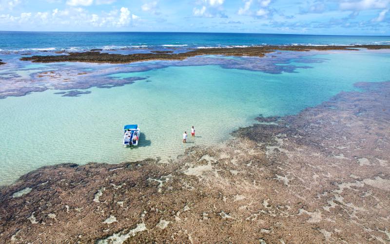 Barquinho ao lado de Adolfo Nomelini e Rafael Carvalho nas piscinas naturais vazias de São José da Coroa Grande